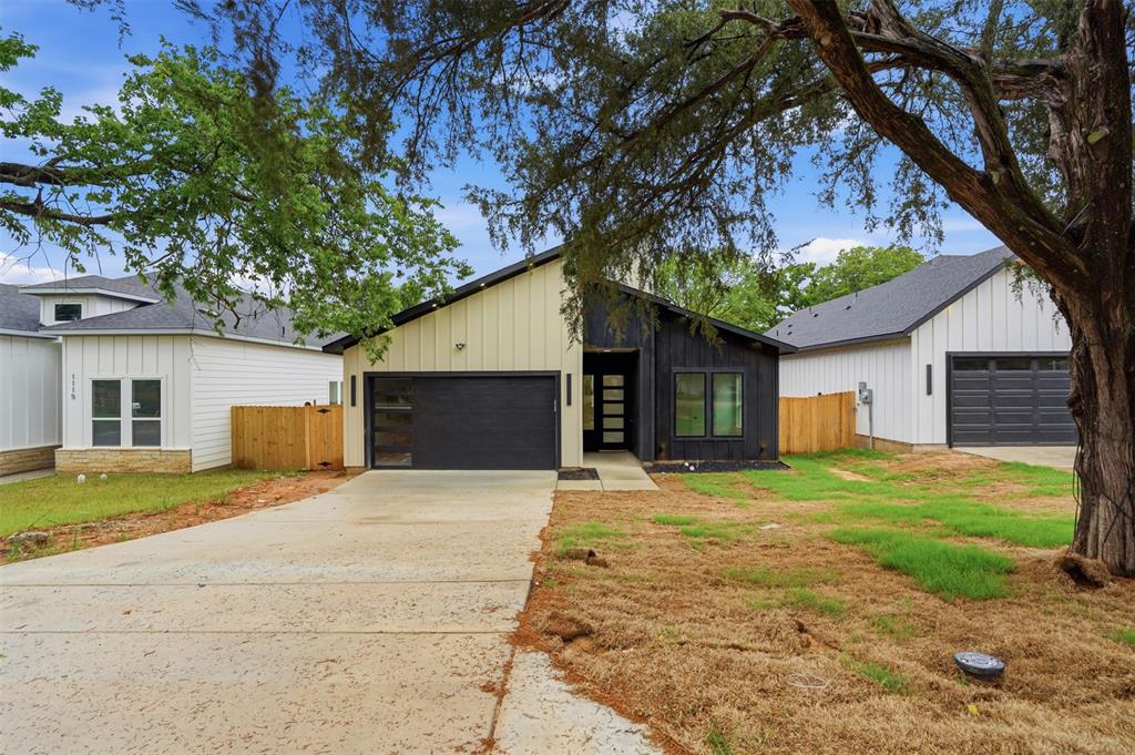 1111 Riverwood Road Dallas, TX 75217 - Photo 3 of 40 Contemporary exterior featuring a black and cream-colored facade, an attached garage with a dark sectional door, a concrete driveway, and a modern entry door with frosted glass panels