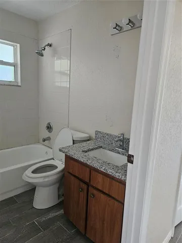 a bathroom with a granite countertop toilet a sink and a bathtub
