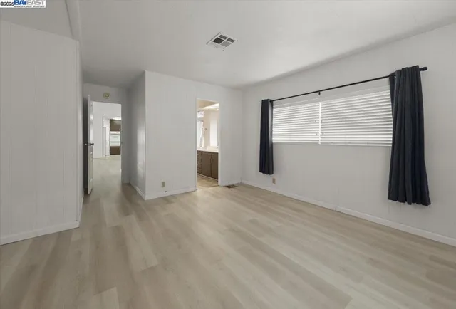 a view of an empty room with window and closet area