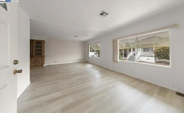 a view of an empty room with wooden floor and windows