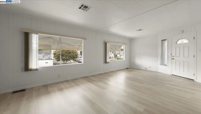 an empty room with wooden floor and windows