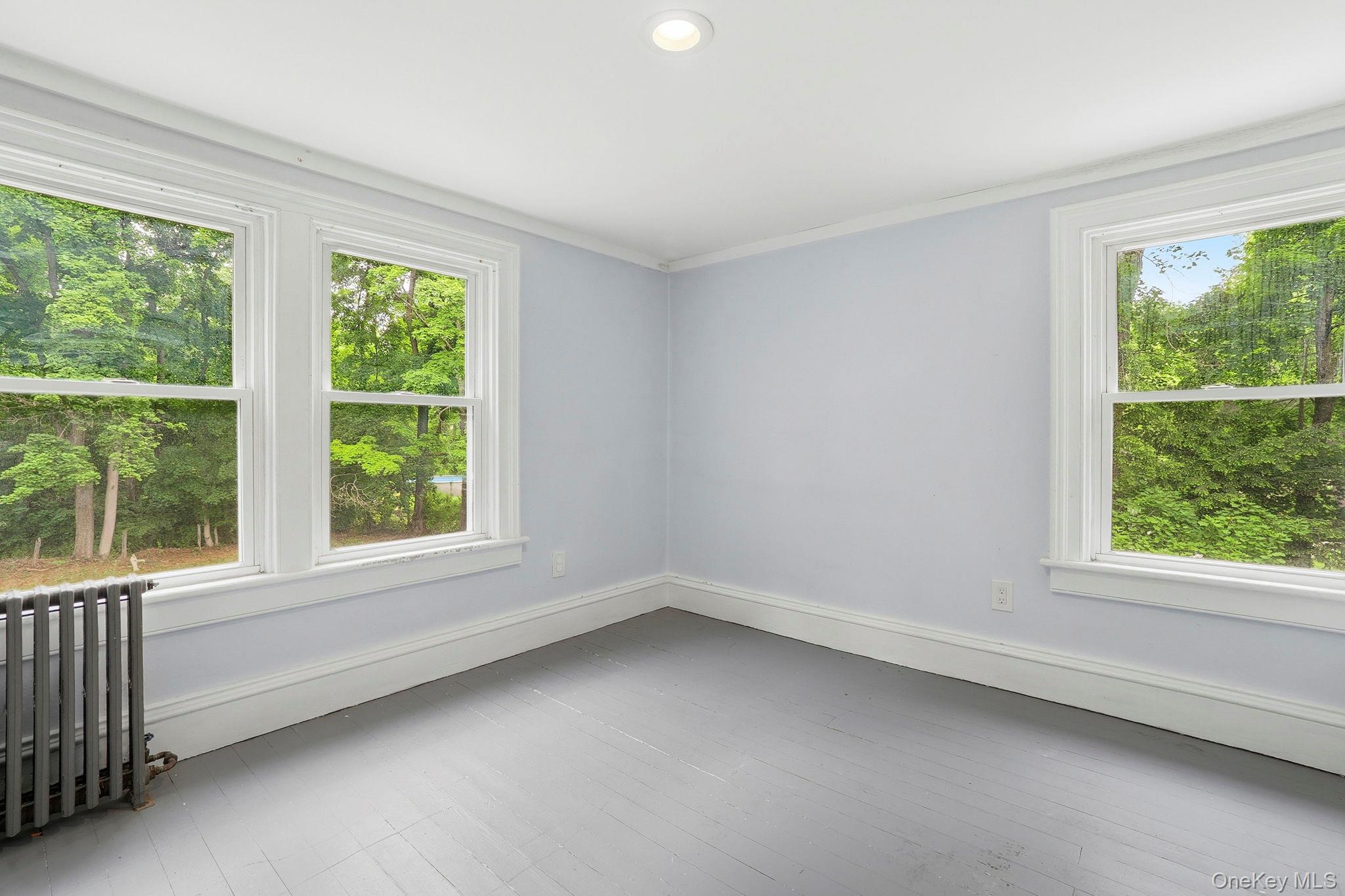 16 Hornbeck Road Poughkeepsie, NY 12603 - Photo 7 of 10 Interior space featuring two windows with white trim, light blue wall paint, gray wood-finish flooring, and a ceiling-mounted recessed light