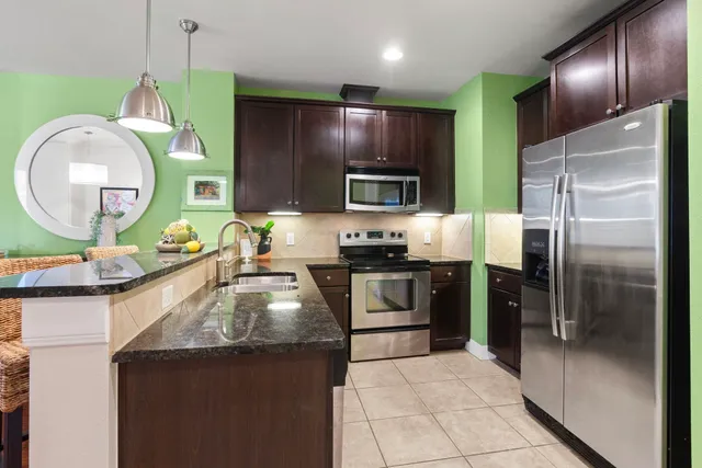 a kitchen with kitchen island granite countertop stainless steel appliances and a sink