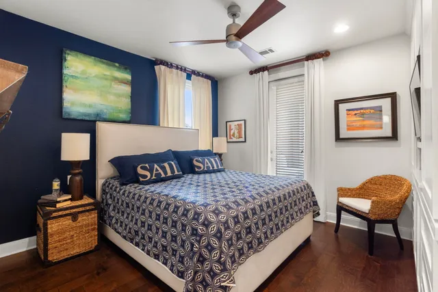 a bedroom with a bed and dresser with wooden floor