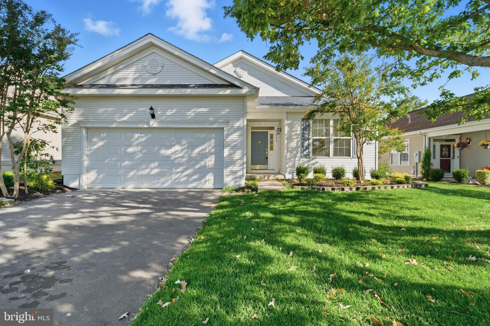 a front view of a house with a garden and trees