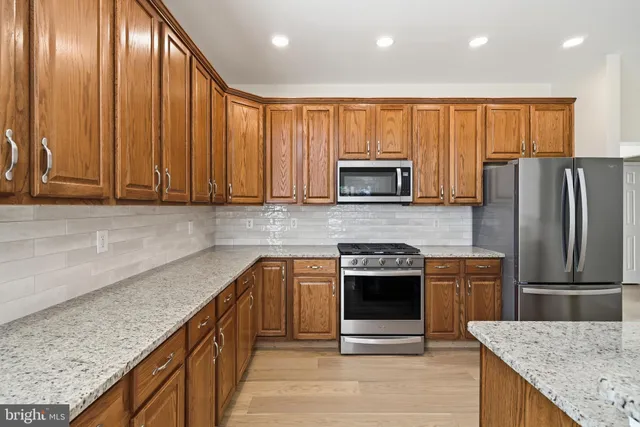 a dining hall with stainless steel appliances kitchen island granite countertop a dining table chairs sink and view living room