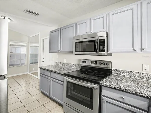a kitchen with granite countertop a stove a microwave and sink