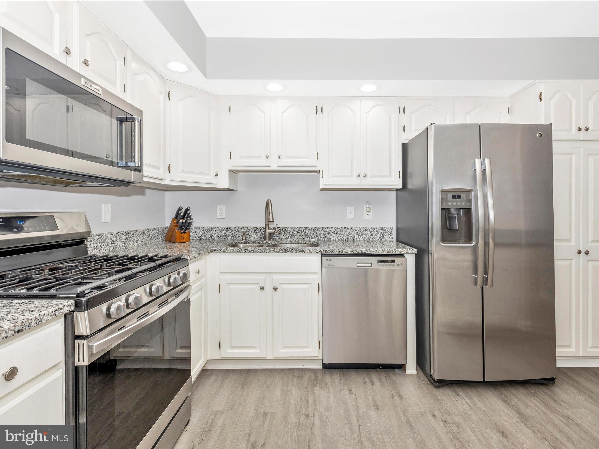 102 Mercer Court, Unit 22 1A Frederick, MD 21701 - Photo 20 of 56 a kitchen with stainless steel appliances granite countertop a refrigerator a stove a sink and white cabinets with wooden floor