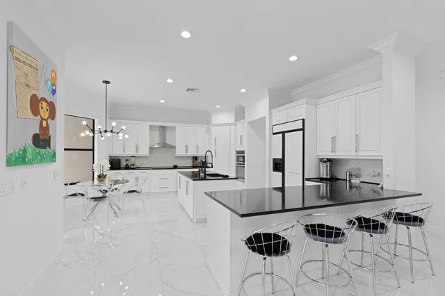 a kitchen with stainless steel appliances kitchen island granite countertop a stove a refrigerator a sink a table and chairs