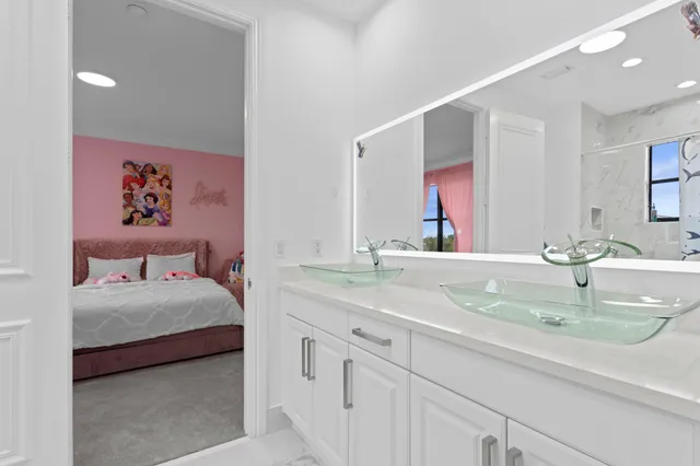 a bedroom with a sink and a large mirror