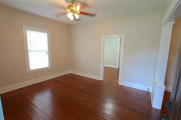 a view of an empty room with wooden floor and a window