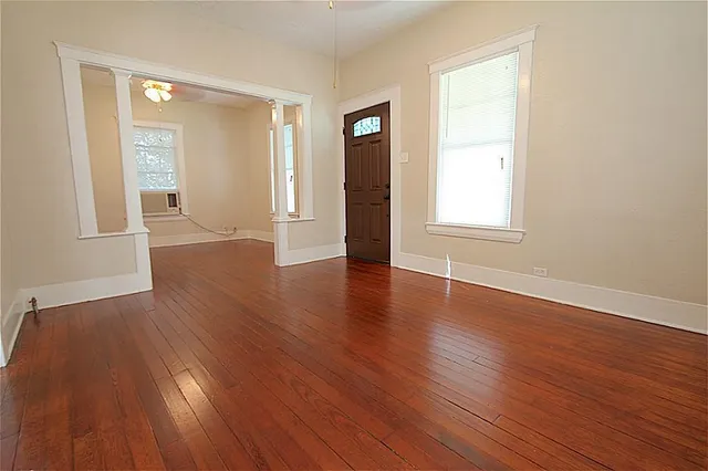 an empty room with wooden floor and windows