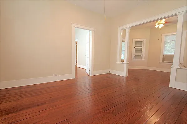 a view of an empty room with wooden floor and a window