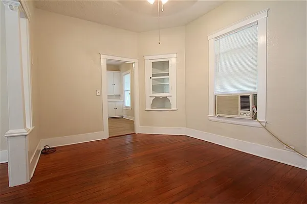 a view of an empty room with wooden floor and a window