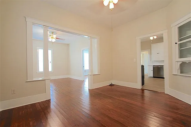 a view of an empty room with wooden floor and a window
