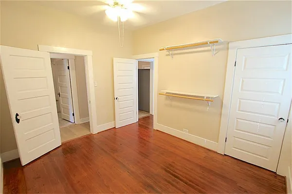 an empty room with wooden floor cabinet and windows