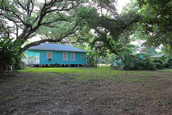 a view of a house with a yard and large trees