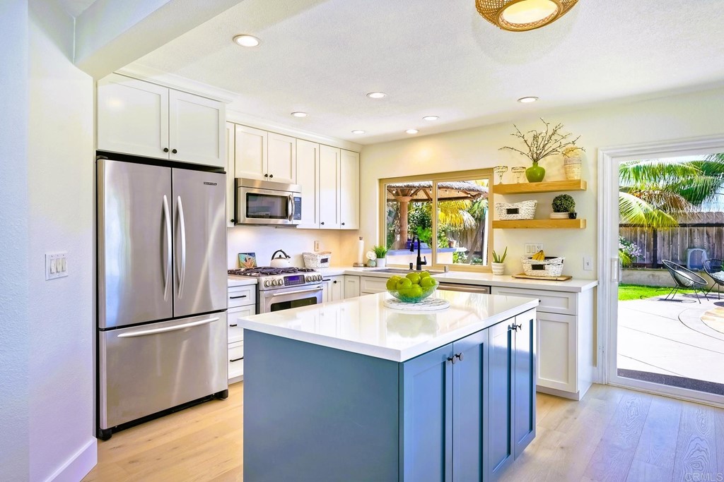 821 Windcrest Drive Carlsbad, CA 92011 - Photo 14 of 53 a kitchen with a refrigerator a stove top oven a sink and dishwasher with wooden floor
