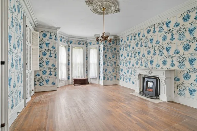 a view of a livingroom with a fireplace wooden floor and a chandelier