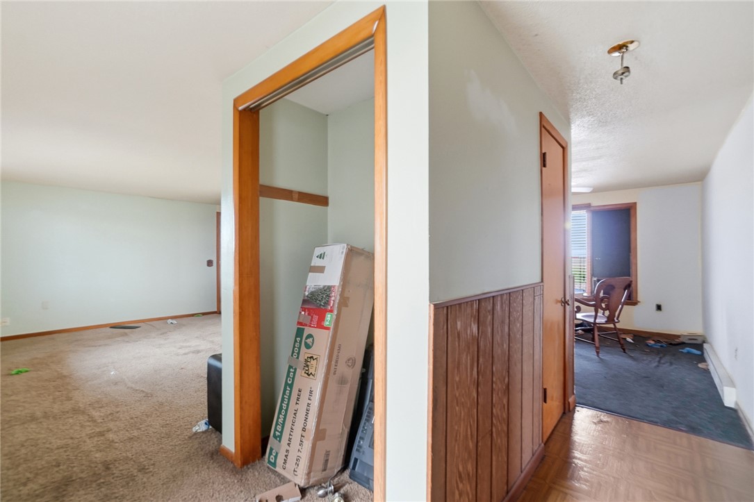 9750 Middlepoint Road Middle Point, OH 45863 - Photo 8 of 43 This interior hallway features a cozy closet, wood paneling, and warm flooring.