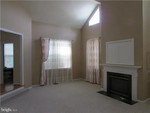 an empty room with windows and fireplace