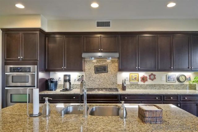 a kitchen with granite countertop a refrigerator a stove and a sink