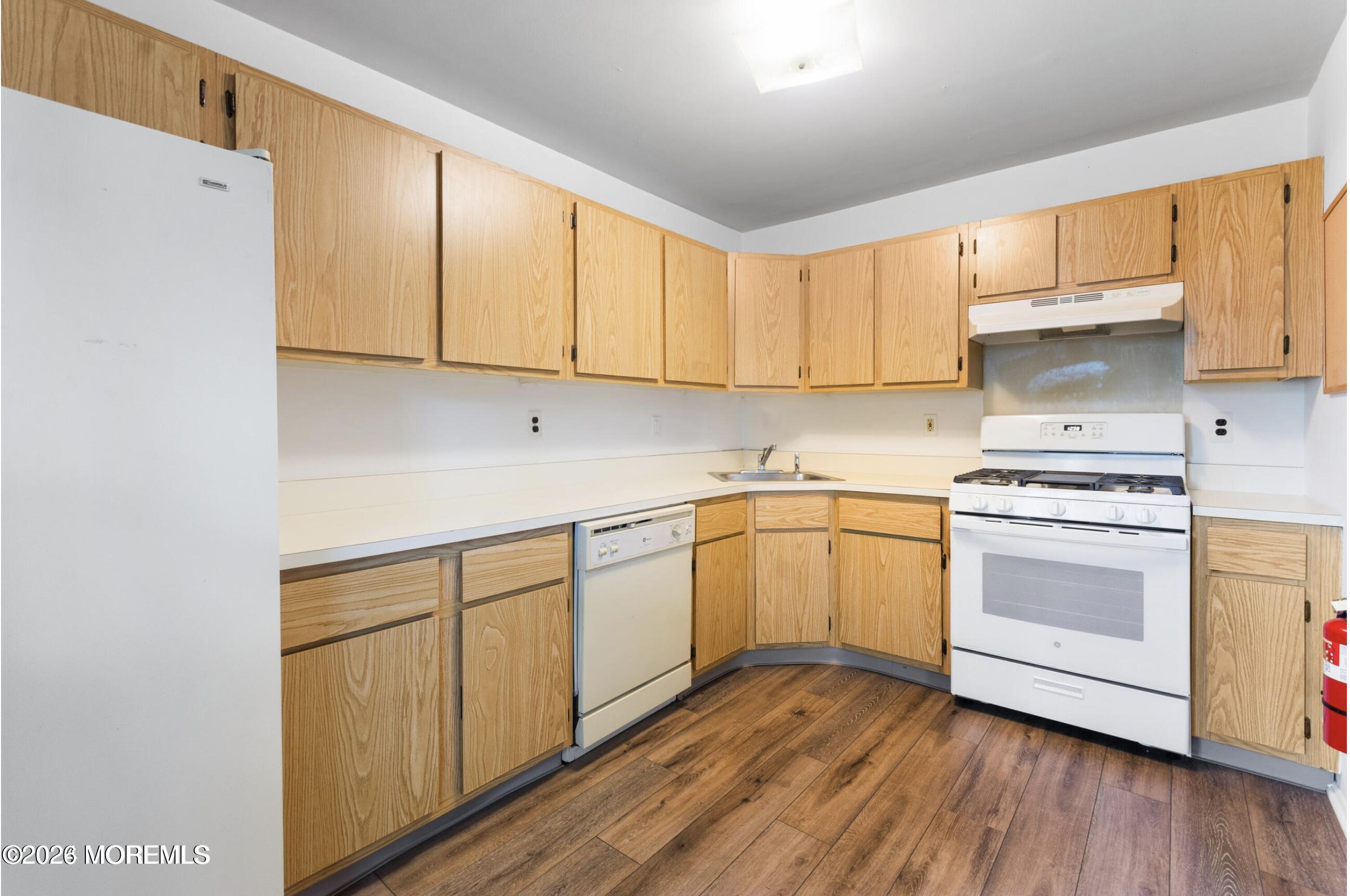 1606 Main Street, Unit R209 Lake Como, NJ 07719 - Photo 5 of 26 a kitchen with granite countertop white cabinets and white appliances