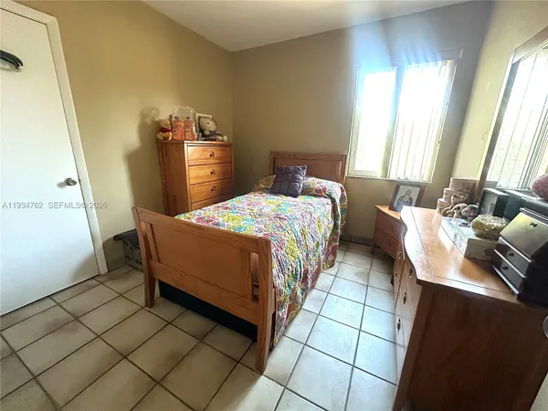a bedroom with a bed and a dresser next to a window