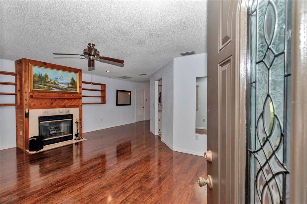 8012 Southwest 109th Place Road Ocala, FL 34481 - Photo 4 of 20 a view of a livingroom with a fireplace a ceiling fan and wooden floor