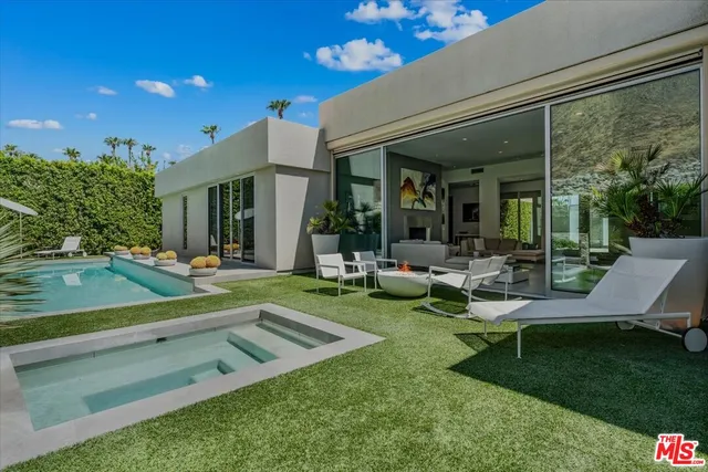 a view of a patio with couches table and chairs with plants and wooden fence
