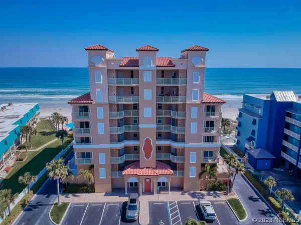 a front view of a building with glass windows and plants