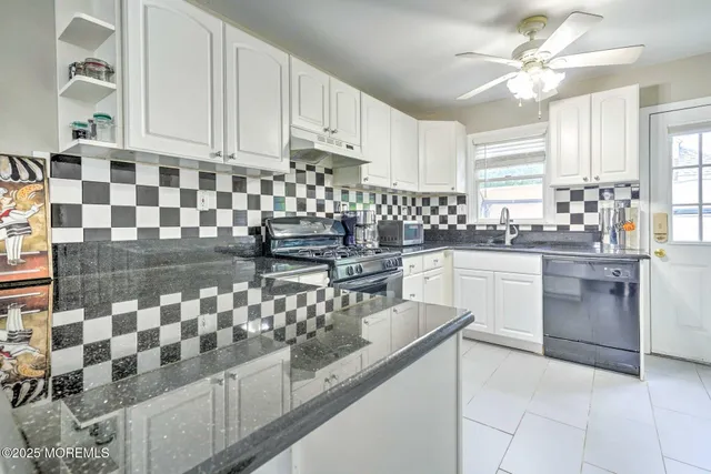 a kitchen with granite countertop a sink a stove a oven a dining table and chairs