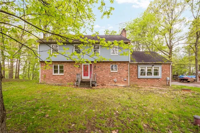 a front view of a house with a garden and tree