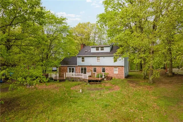 a view of a house with a big yard plants and large trees