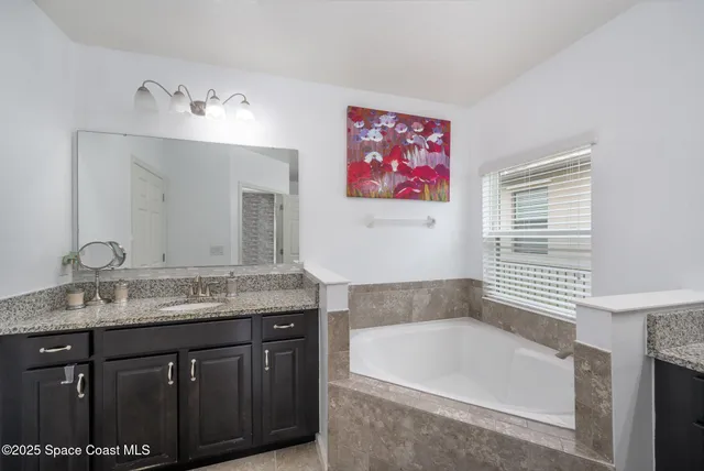 a bathroom with a granite countertop bathtub sink and mirror