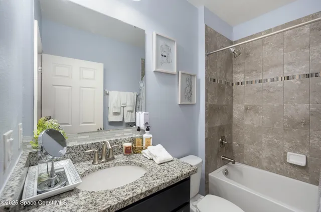 a bathroom with a granite countertop sink mirror and a bathtub