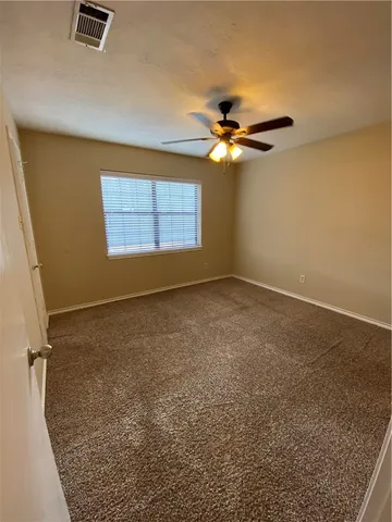 an empty room with windows and fan
