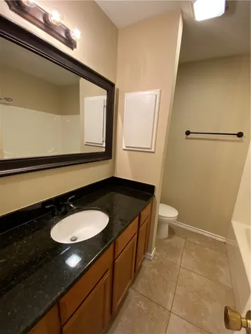 a bathroom with a granite countertop sink a toilet a mirror and vanity
