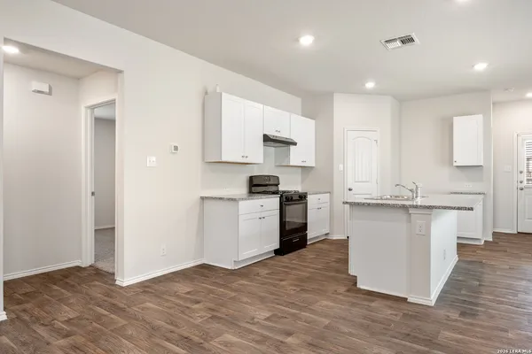 a kitchen with granite countertop a stove top oven sink and cabinets