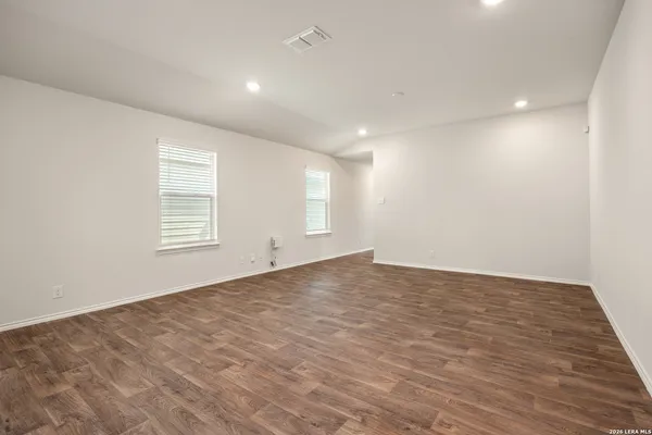 an empty room with wooden floor and windows