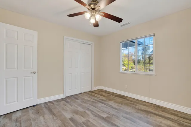 a view of an empty room with window and chandelier fan
