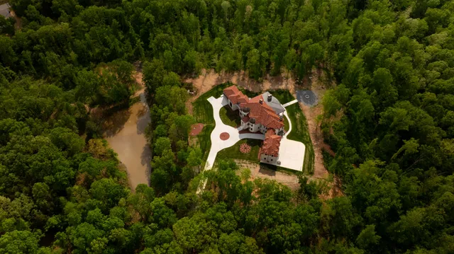 an aerial view of residential house with outdoor space and trees all around