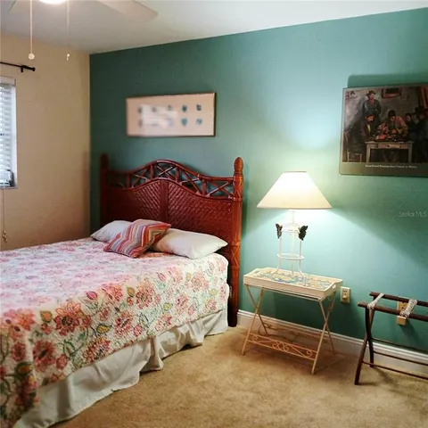 a bedroom with bed and a lamp on dresser