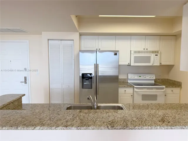 a kitchen with a refrigerator sink and cabinets