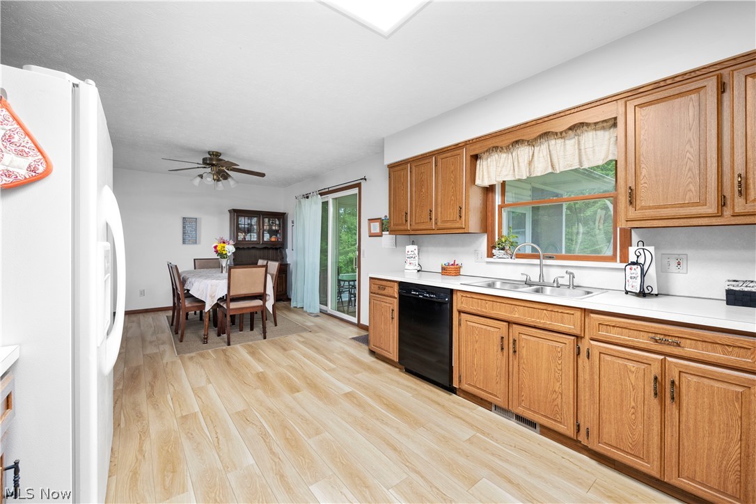 Kitchen with ceiling fan, light hardwood / wood-style flooring, white fridge, dishwasher, and sink