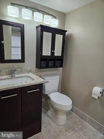 a bathroom with a granite countertop toilet sink and mirror