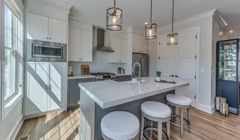 a kitchen with stainless steel appliances a table chairs and microwave