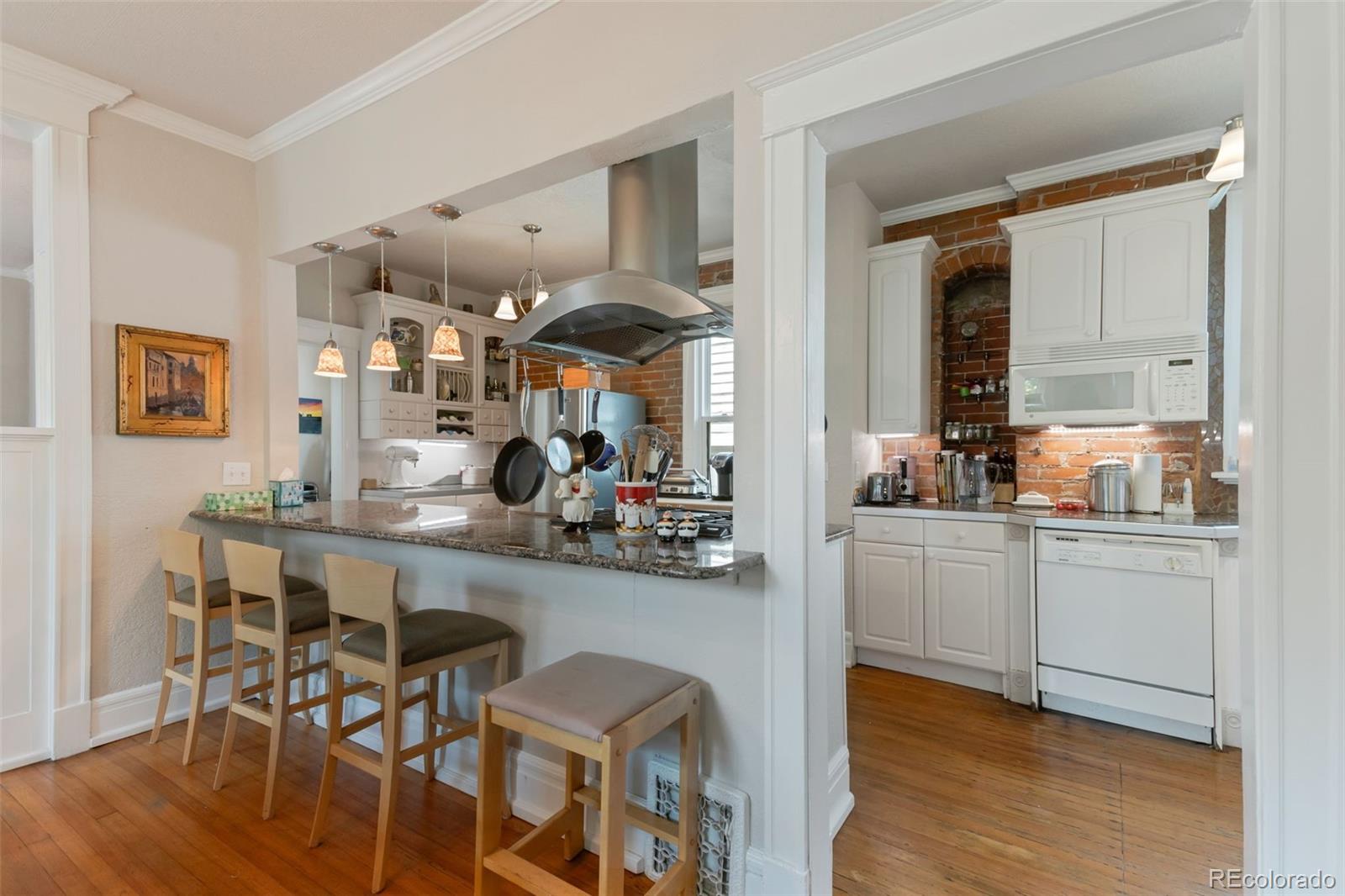 3732 Alcott Street Denver, CO 80211 - Photo 10 of 19 a kitchen with stainless steel appliances kitchen island wooden floors and white cabinets