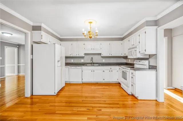 a kitchen with stainless steel appliances granite countertop a stove a sink dishwasher and a refrigerator with wooden floor