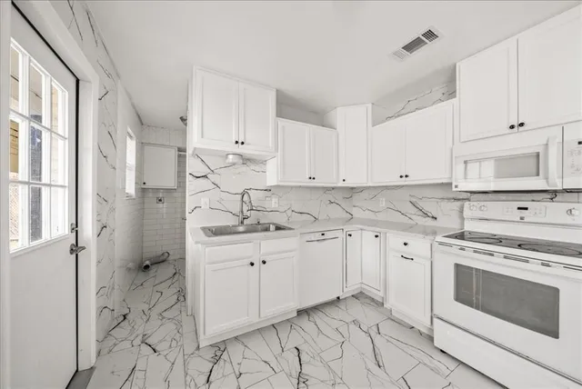 a kitchen with granite countertop white cabinets and white appliances